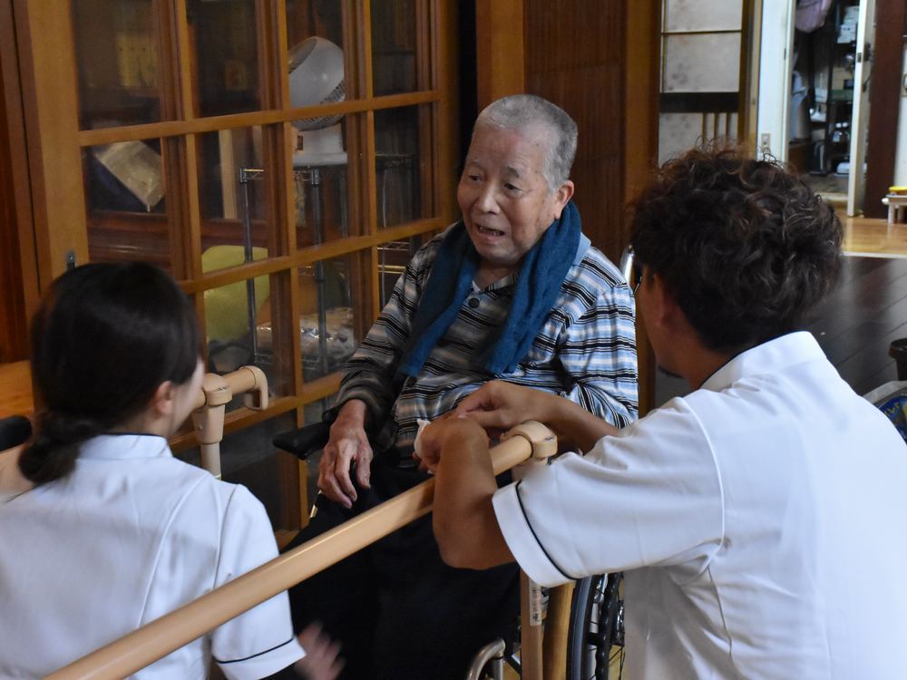 車いすの男性と向き合い、話を聞くセラピスト